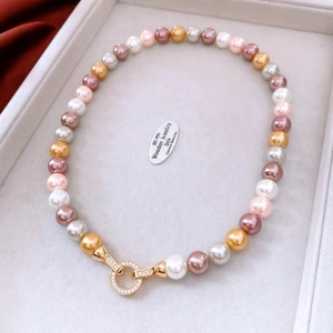 Detail of colorful round pearls with sparkling gold pave crystal clasp on white tray