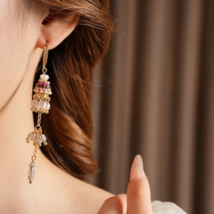 Détail de boucles d'oreilles bohèmes à pampilles avec perles et cristaux sur un modèle