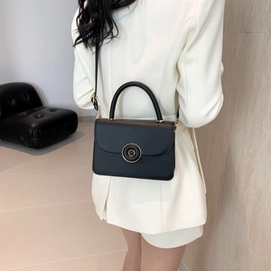 Minimalist black faux leather crossbody bag with gold round buckle and adjustable strap