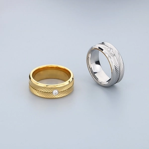 Close-up of gold and silver feather-textured rings with sparkling inset crystals