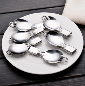 Detailed view of six stainless steel folding sporks arranged on a ceramic plate for camping