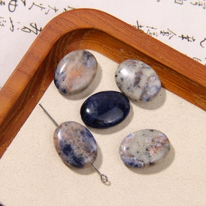 Macro view of five oval natural stone beads with mixed textures on a wooden tray