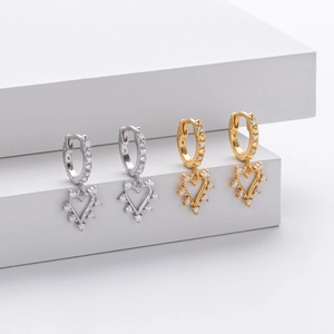 Detailed view of silver and gold heart earrings set with sparkling zircon stones