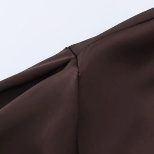 Detailed view of the smooth satin fabric texture and precise stitching on a brown blouse