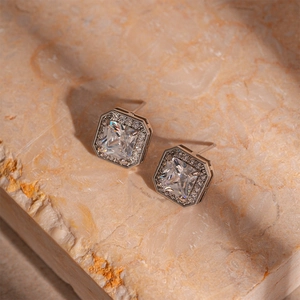 Close-up of silver square halo stud earrings with cubic zirconia on marble background