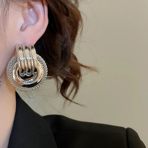 Gros plan d'un mannequin portant des boucles d'oreilles rondes torsadées en métal argenté