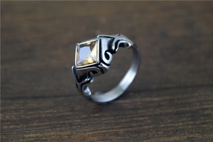 Macro detail of vintage stainless steel ring featuring a square yellow gemstone inlay