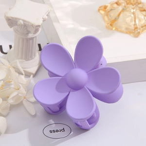 Detail of a matte lavender purple flower hair claw clip on a stylish decorative pedestal
