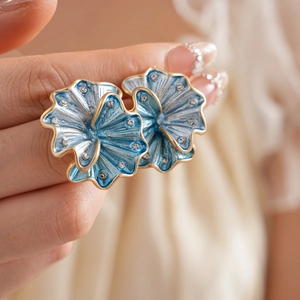 Macro shot of blue flower earrings with gold edges and sparkling crystals