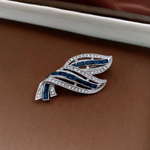 Detail of a silver-toned brooch with navy blue rectangular stones and white zircons