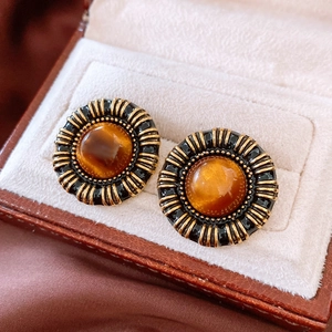 Detailed close-up of vintage resin round stud earrings with black and gold textured edges