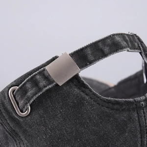 Close-up of adjustable metal buckle and twill cotton texture on washed denim baseball cap
