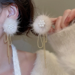 Detail of plush flower earring with soft fur ball and hanging golden bead tassels