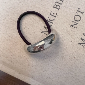 Detail of high-elasticity hair tie with polished silver curved metal accent on burlap texture