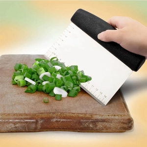 Stainless steel dough scraper with black handle and 14cm scale on wooden cutting board