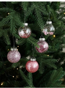 Close-up of pink decorative Christmas ornaments with various textures hanging on a tree