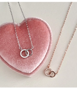 Detailed macro of silver and rose gold interlocking double ring necklaces on velvet