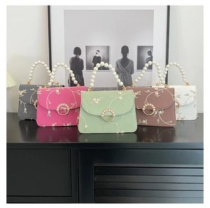 Detail of floral embroidery and pearl handle on five elegant square handbags