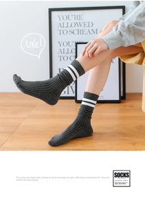 Detailed texture of dark grey ribbed knit socks with white stripes on a wooden floor
