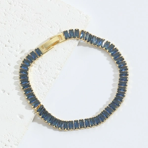 Detailed macro view of deep blue rectangular gemstone set in a gold minimalist bracelet