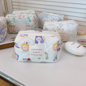 Quilted cotton cosmetic bags with floral patterns on a sunlit table in soft shadows