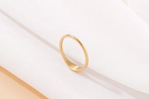 Polished gold signet ring on white silk fabric with soft lighting and elegant shadows