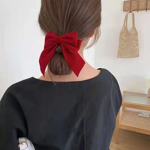 Large red bow hair clip for girls shown on the back of the head in a soft home setting