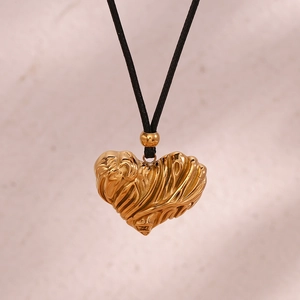 Detailed view of gold heart pendant with unique crinkled texture on a black cord