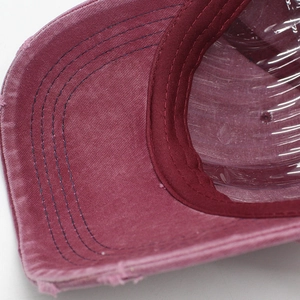 Detail of burgundy distressed denim baseball cap with frayed edges and 4-row stitching