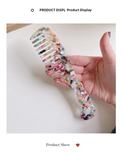 Detail showing the colorful marble pattern and ergonomic handle of the wide-tooth comb