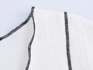 Gros plan détaillé sur un tissu blanc avec liseré noir et coutures renforcées