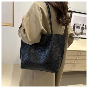 Close-up of the black tote bag featuring a glossy crocodile pattern and long shoulder straps