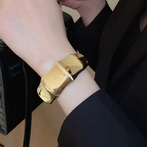 Close-up of a wide gold bamboo-style cuff bracelet with a high-polished mirror finish