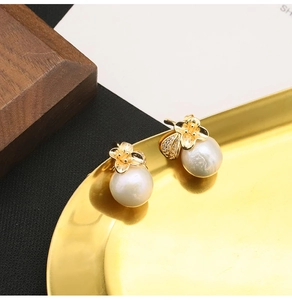 Macro shot of gold floral earrings with white pearls and sparkling cubic zirconia details