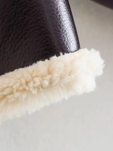 Detail showing dark brown pebbled leather texture and white faux shearling trim