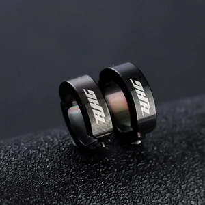 Minimalist black metal ear cuffs with white ZAHG lettering on a textured surface