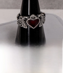 Detail of vintage silver titanium steel ring with red heart inlay and ornate scrollwork