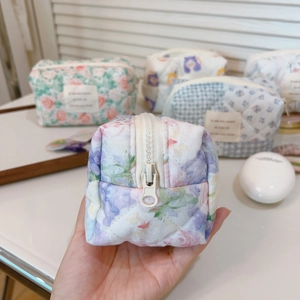 Detailed macro view of quilted floral and plaid cotton cosmetic bag with zipper
