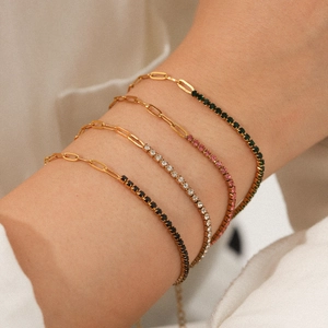 Detail of stacked gold zircon paperclip bracelets showing rhinestone colors on a model wrist
