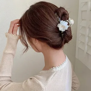 Detail of camellia flower hair claw clip with pearl center on tortoiseshell resin base