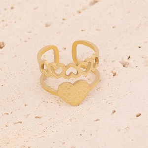 Dettaglio di un anello dorato a doppio strato con cuori su pietra beige