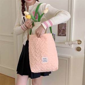 Detailed heart-quilted pink tote bag with green handles and brand label on front