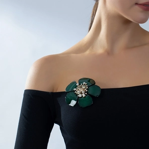 Elegante dunkelgrüne Kamelien-Brosche mit Kristallzentrum auf schwarzem Oberteil