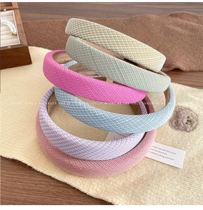 Detail of colorful woven padded headbands in various candy colors on a cozy wood table