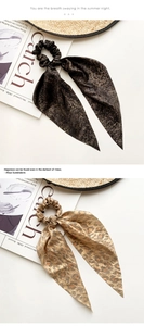 Detailed view of silk leopard print and solid brown scrunchies with long ribbons on a magazine