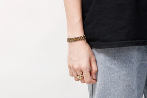 Detail of silver and gold watch-strap style stainless steel ring and bracelet on model