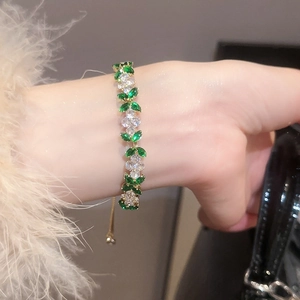 Close-up of gold adjustable bracelet with green marquise stones and flower rhinestones