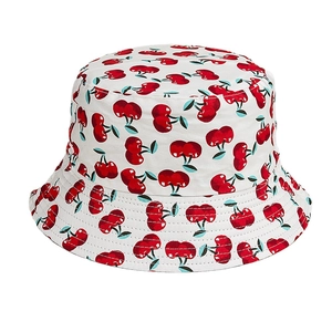 White canvas bucket hat with red cherry print for women featuring a wide sun brim