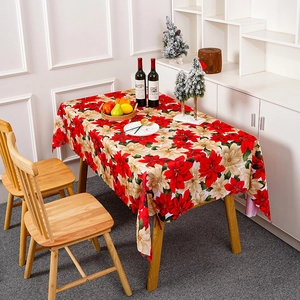 Détail d'une nappe de Noël festive avec un imprimé floral de poinsettia rouge et crème