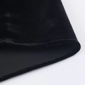 Détail de la texture en velours noir et poignet élastique sur une robe courte